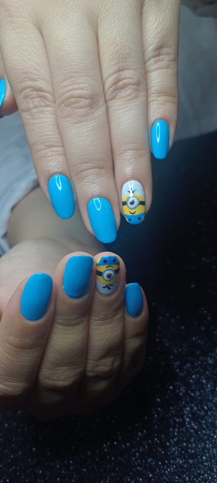 Uñas ovaladas en azul cielo brillante con dos Minions pintados a mano en las uñas de acento.