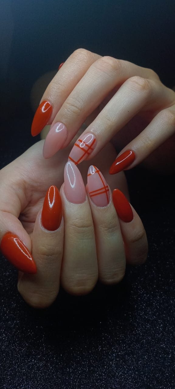 Uñas almendradas largas en rojo brillante combinadas con nude y cuadros rojos tipo tartán.
