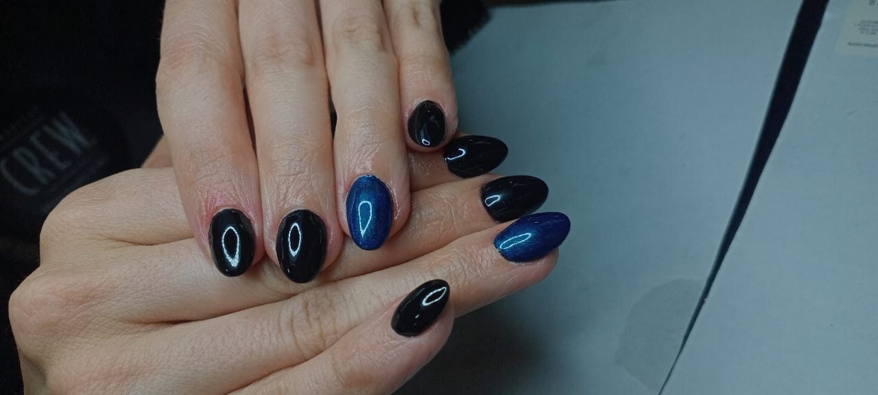 Uñas almendradas en negro brillante con dos uñas en azul ojo de gato.